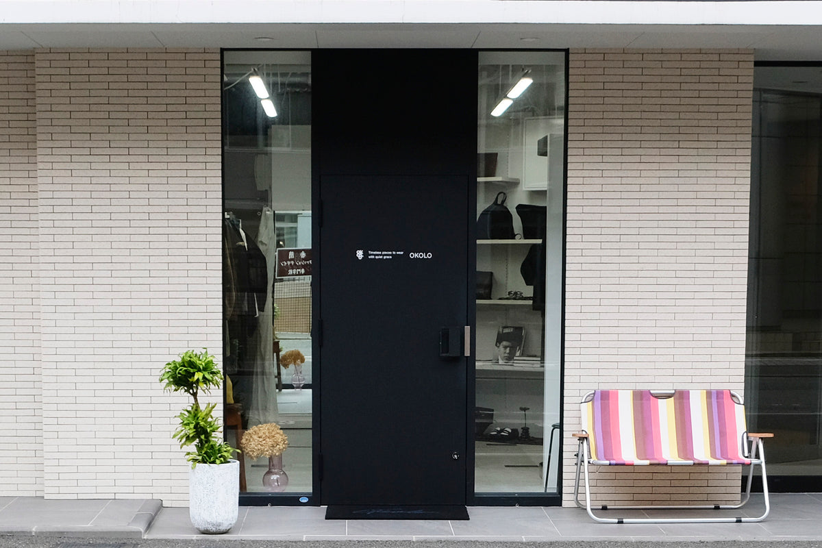 福岡・大手門のセレクトショップOKOLOの外観。黒い入口とストライプのベンチ。